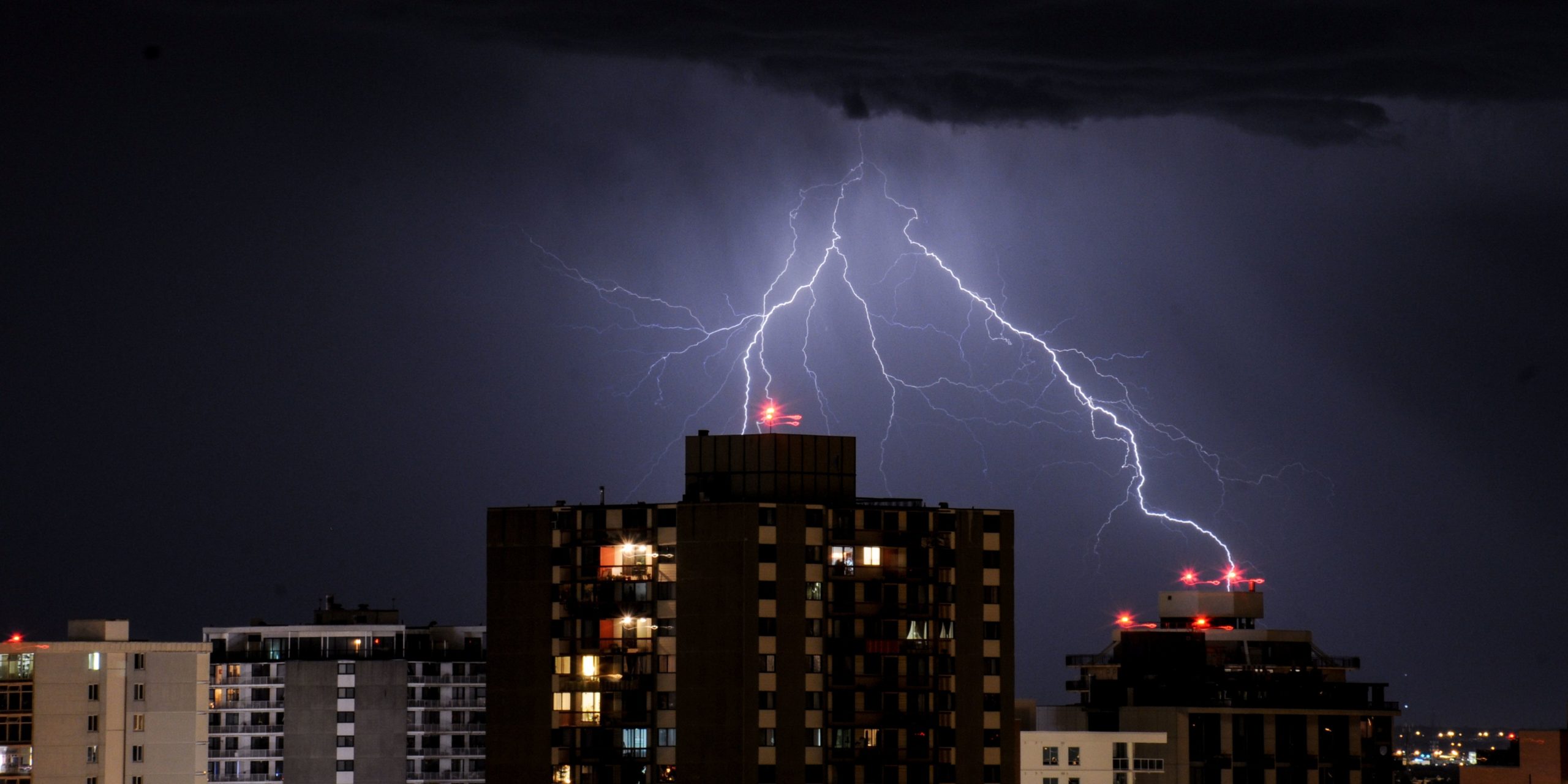 A lightning stroke in the night sky on high-rise buildings.